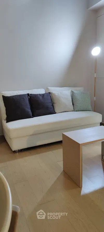Modern living room with white sofa and wooden coffee table, perfect for cozy relaxation.
