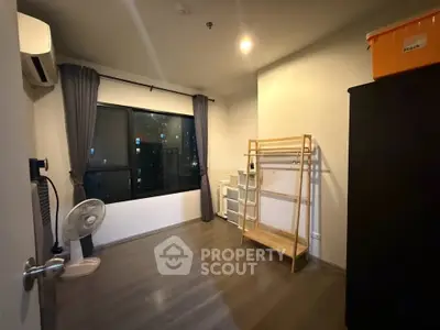 Spacious unfurnished room with large window and wooden flooring in modern apartment.