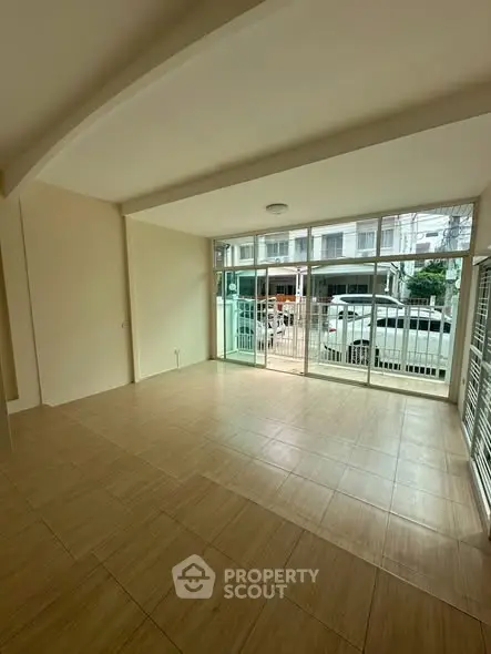 Spacious living room with large windows and tiled flooring, perfect for natural light.