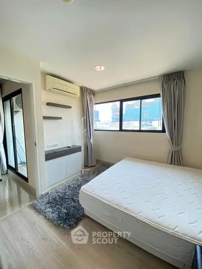 Modern bedroom with large windows and air conditioning in a high-rise apartment.