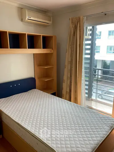 Cozy bedroom with single bed, built-in shelves, and balcony access in modern apartment.