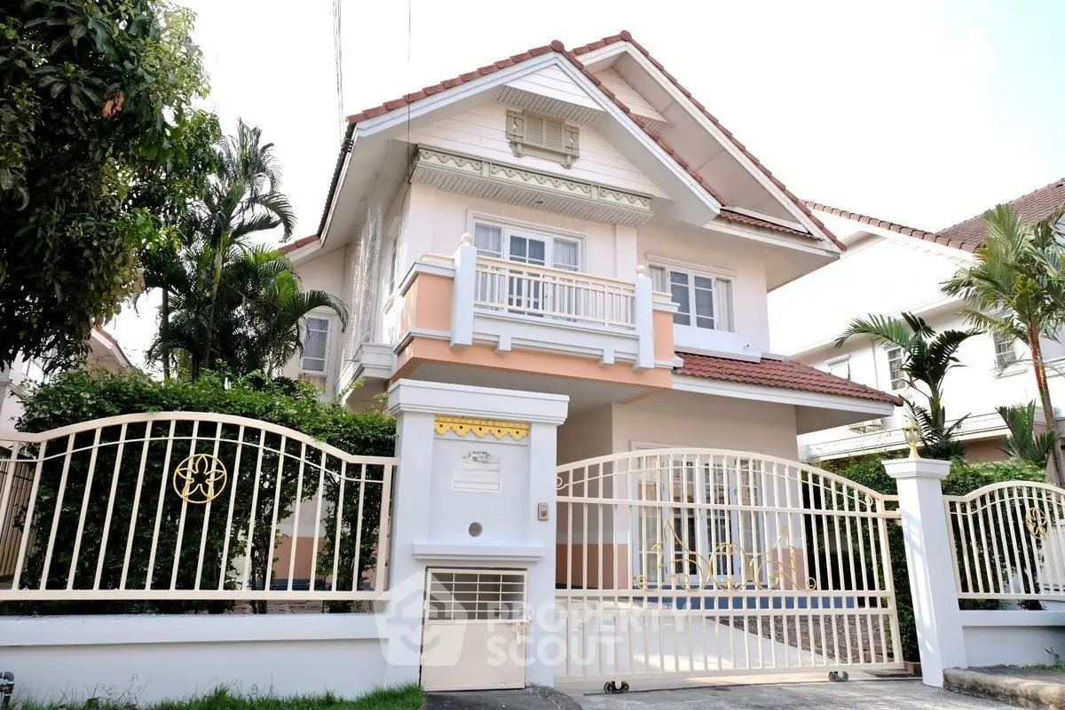 Charming two-story house with a gated entrance and lush greenery, perfect for family living.