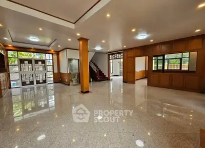 Spacious open-plan living room with elegant wooden accents and large windows.