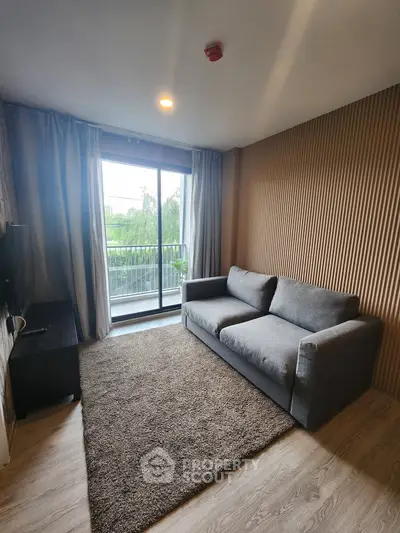 Modern living room with gray sofa, large window, and balcony view in stylish apartment.