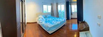 Spacious bedroom with wooden flooring and large windows offering natural light and views.