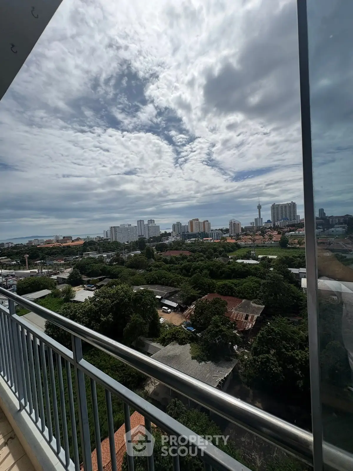 Stunning cityscape view from a high-rise balcony with lush greenery and skyline.