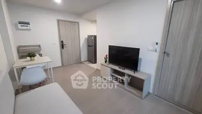 Modern living room with sleek furniture and open layout, featuring a TV and dining area.