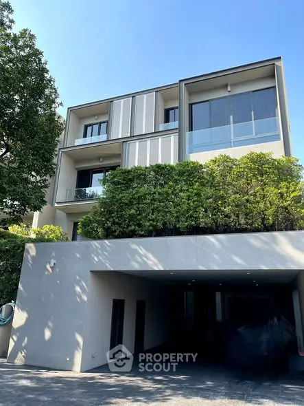 Modern multi-story building with lush greenery and spacious balconies.
