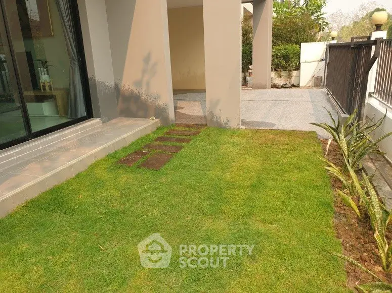 Charming garden entrance with lush green lawn and modern architecture.