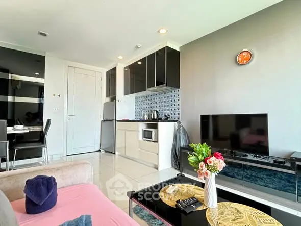 Modern living room with open kitchen, stylish decor, and natural light.