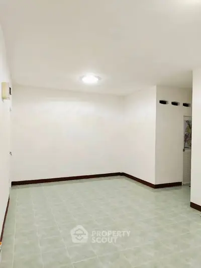 Spacious empty room with tiled floor and bright lighting, ideal for customization.