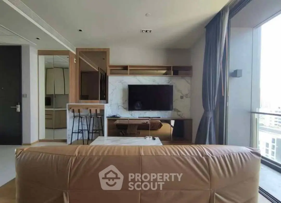 Modern living room with sleek furniture and large TV, featuring a spacious open layout and natural light.