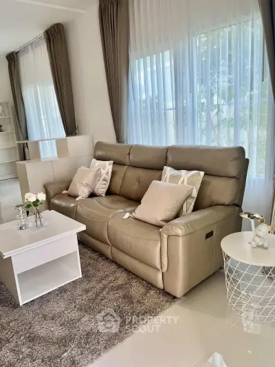 Elegant living room with plush leather sofa, chic decor, and large windows for natural light.