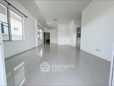 Spacious empty living room with glossy tiled floors and large windows.