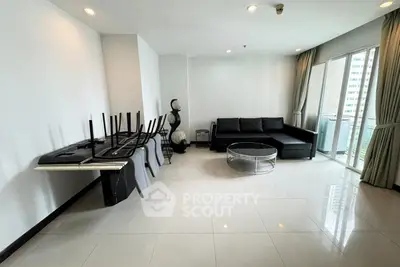 Spacious modern living room with sleek furniture and large windows offering city views.