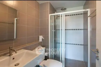 Modern bathroom with sleek shower and stylish sink in contemporary apartment.