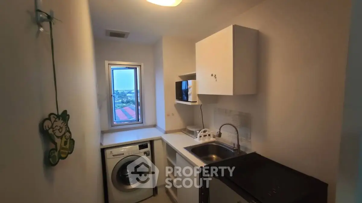 Compact laundry room with washing machine and sink, bright window view.