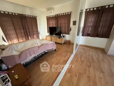 Spacious bedroom with wooden flooring and mirrored wardrobe, featuring a cozy bed and entertainment unit.