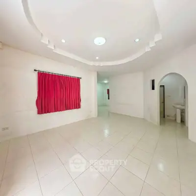 Spacious unfurnished living room with tiled flooring and red curtains