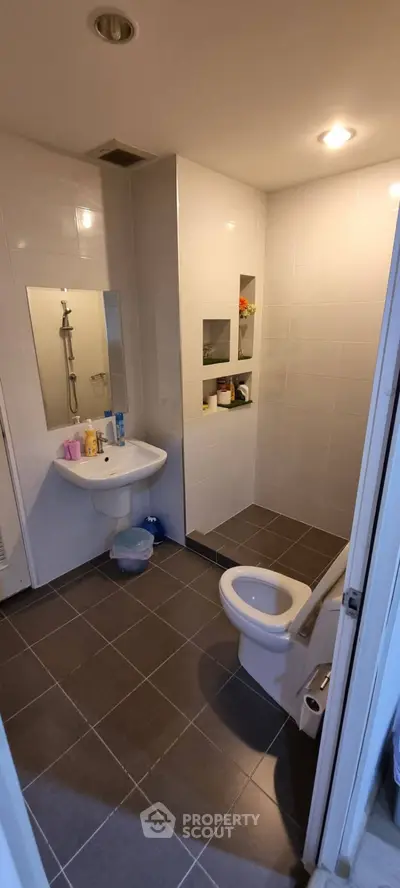 Modern bathroom with sleek design, featuring a shower, sink, and toilet in a compact layout.