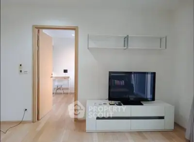 Modern living room with sleek TV stand and open door to adjacent room, showcasing minimalist design.