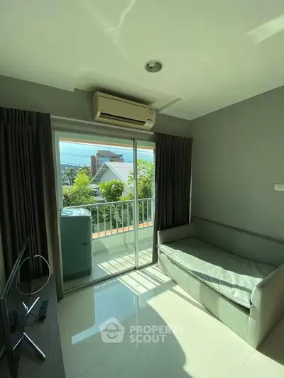 Bright living room with balcony access and air conditioning, perfect for relaxation and enjoying natural light.