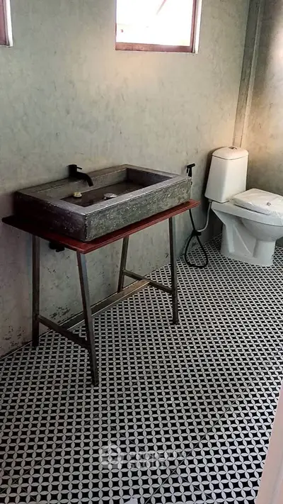 Modern minimalist bathroom with unique concrete sink and patterned tile flooring.