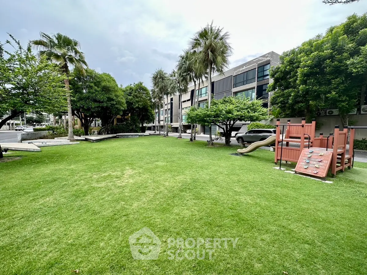 Spacious green garden with playground in modern residential complex.
