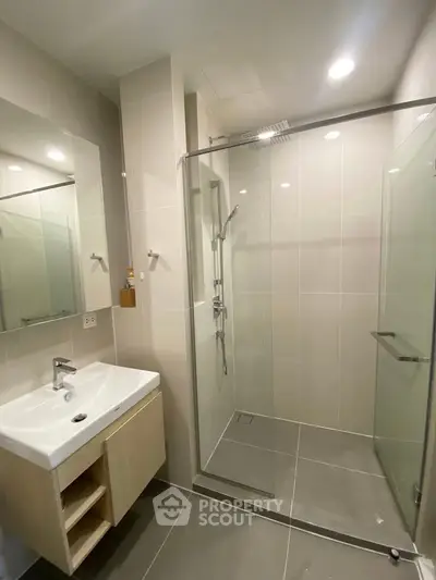 Modern bathroom with glass shower and sleek vanity in contemporary home.
