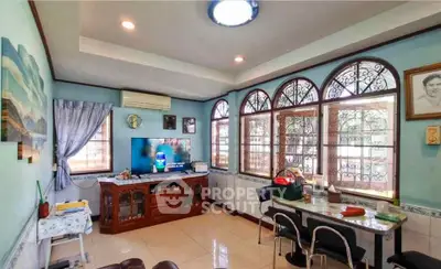 Charming living room with vintage decor and natural light, featuring arched windows and cozy seating area.