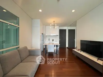 Modern living room with sleek furniture and open kitchen layout, featuring hardwood floors and contemporary design.