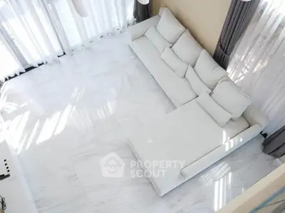 Spacious modern living room with white marble flooring and large sectional sofa.