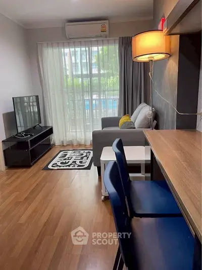 Modern living room with stylish decor and natural light, featuring a cozy sofa and sleek TV setup.