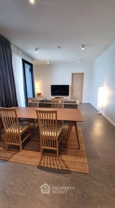 Spacious modern living room with dining area and large windows in a stylish apartment.