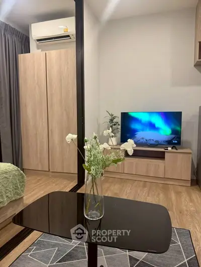 Modern studio apartment with stylish decor and cozy ambiance, featuring a sleek TV setup and elegant furnishings.