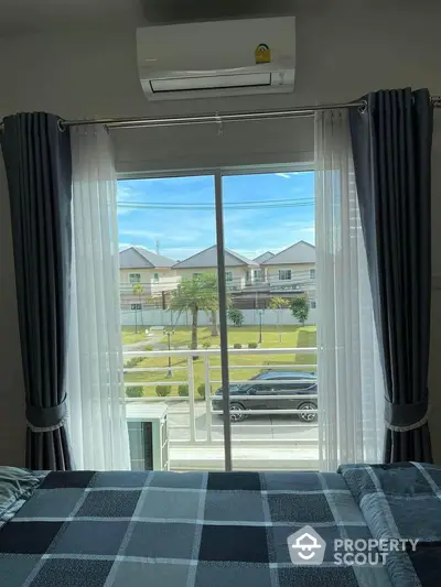 Cozy bedroom with balcony view overlooking suburban street and houses