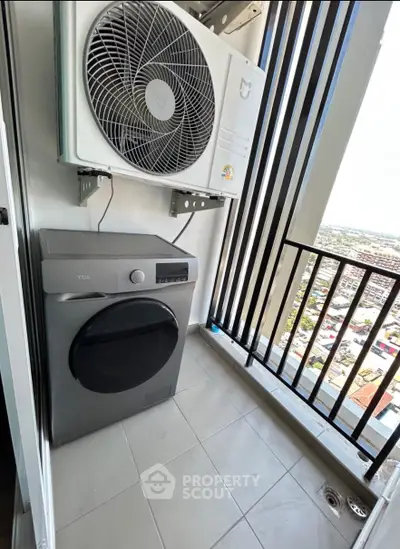 Compact balcony with washing machine and air conditioning unit, offering a city view.