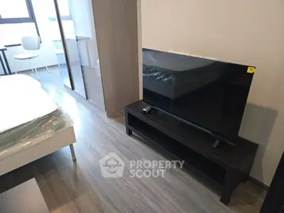 Modern bedroom with sleek TV and stylish furniture, perfect for urban living.