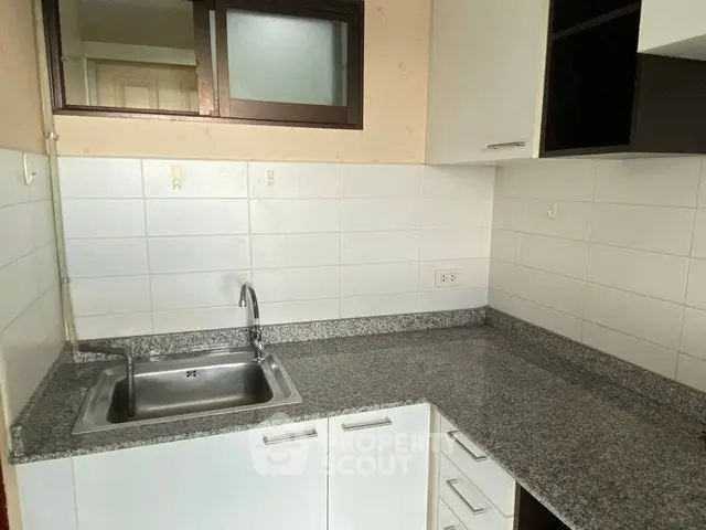Modern kitchen with granite countertops and sleek cabinetry in a contemporary apartment.