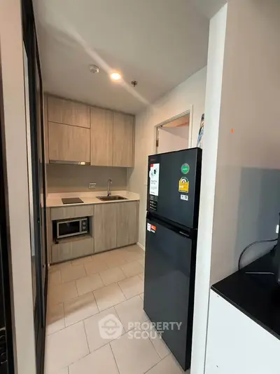Modern compact kitchen with sleek cabinetry and appliances in a stylish apartment.