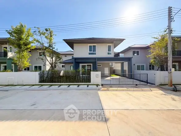 Modern two-story house with gated driveway and sunny exterior.