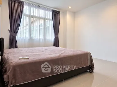 Spacious bedroom with large window and elegant curtains in modern apartment.