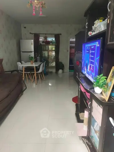 Spacious living room with modern decor and dining area, featuring a cozy sofa and entertainment setup.