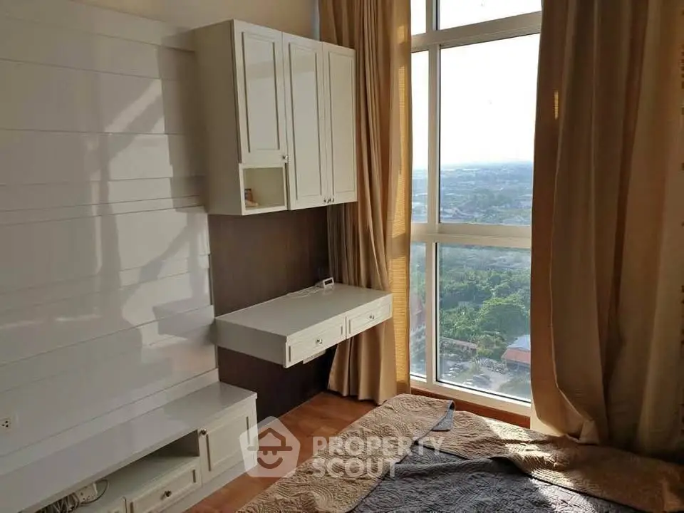 Bright bedroom with large window offering stunning city view and modern built-in furniture.