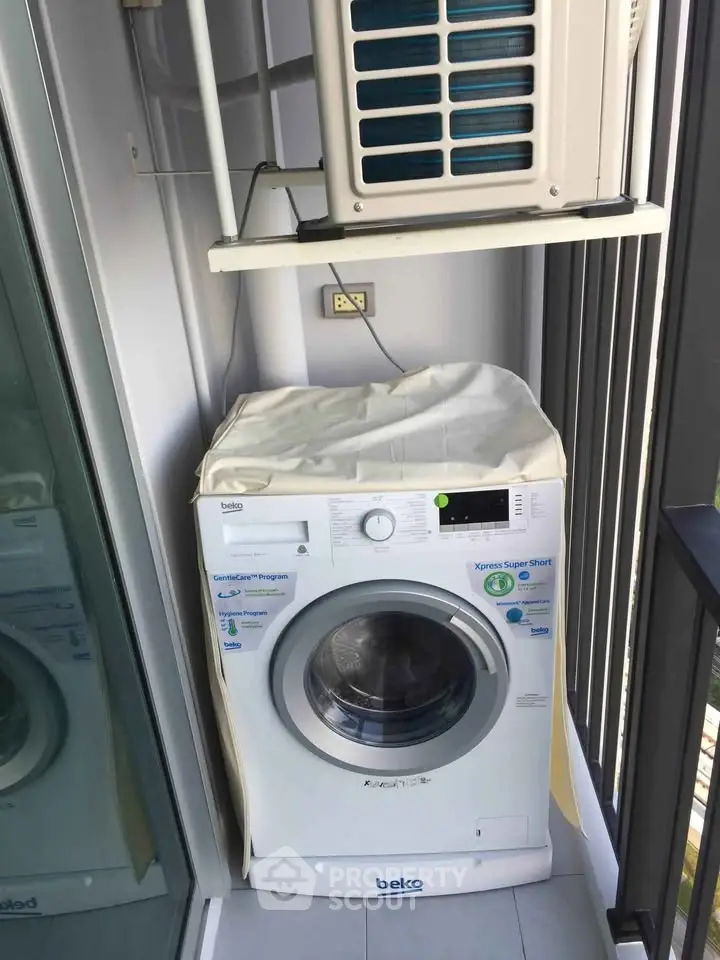 Compact balcony with washing machine and air conditioning unit in modern apartment.