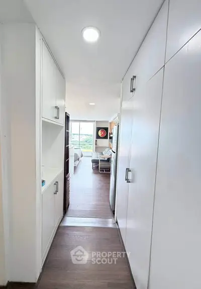 Modern apartment hallway leading to a bright living area with large windows and stylish decor.
