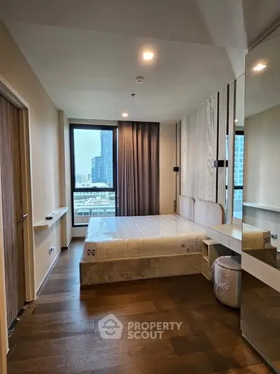 Modern bedroom with city view, featuring hardwood floors and stylish decor in a high-rise apartment.