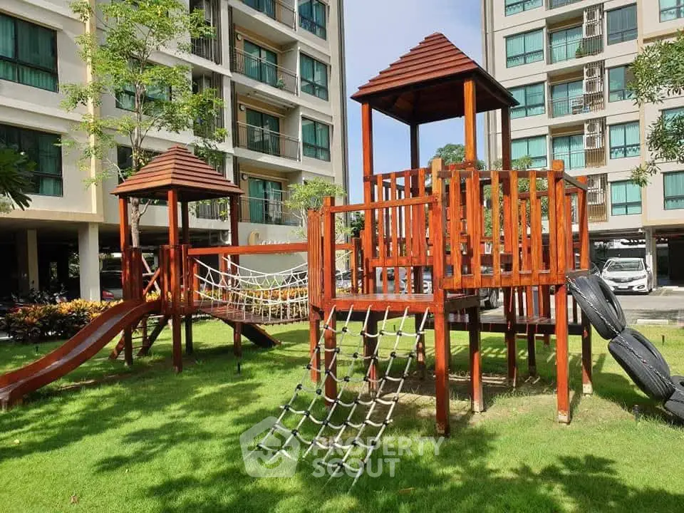 Modern apartment building with children's playground in lush green garden.