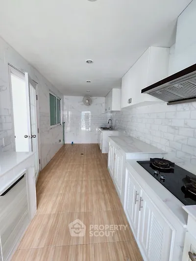 Sleek modern kitchen with gas stove and white cabinetry in a narrow layout.