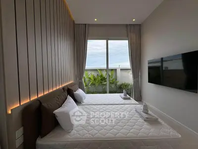 Modern bedroom with twin beds, large window, and wall-mounted TV in a stylish apartment.